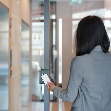 Young officer woman holding a key card to lock and unlock door for access entry. Door access control. Back view.