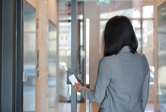Young officer woman holding a key card to lock and unlock door for access entry. Door access control. Back view.